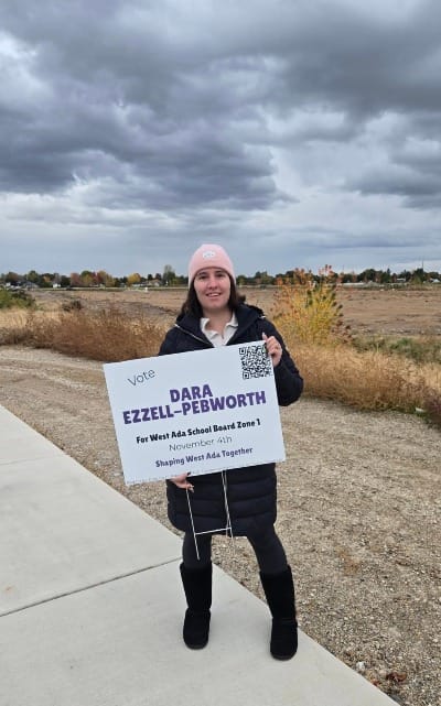 Woman holding campaign sign in front of unimproved lot